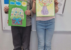 Dzieci stoją i prezentują prace na konkurs plastyczny