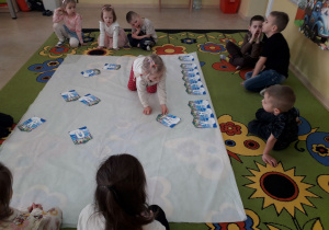 Dzieci podczas zajęcia na dywanie układają napis "W marcu jak w garncu" .