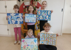 Dziewczynki prezentują prace na konkurs plastyczny.