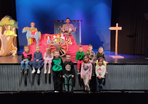 Dzieci pozują do zdjęcia na tle scenografii teatralnej.