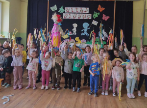 Dzieci w grupie pozują do zdjęcia na holu przedszkolnym na tle dekoracji.