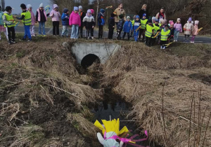 Dzieci stoją w oddali. Przed nimi Marznna wrzucona do wody.
