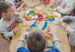 Dzieci psiedzą przy stolikach wykonują gaiki.