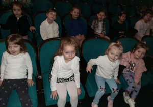 Przedszkolaki siedzą na widowni i czekają na spektakl.
