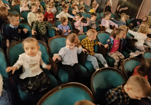 Dzieci siedzą w teatrze i czekają na przedstawienie