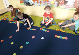 Dzieci podczas zabawy matematycznej na dywanie dopasowują połówki pisanek