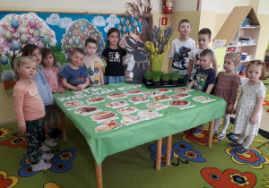 Dzieci pozują do zdjęcia wokół stołu wielkanocnego.