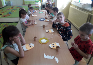 Dzieci przy stolikach podczas tworzenia wielkanocnego kurczaczka.