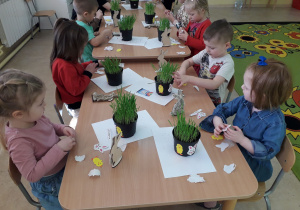 Dzieci przy stolikach komponują stroik wielkanocny.