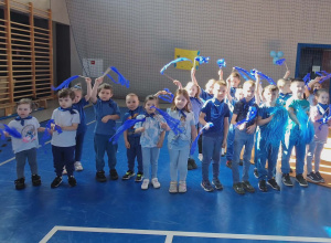 Dzieci w grupie ubrane na niebiesko na hali sportowej