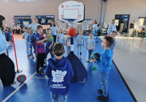 Dzieci rzucają piłką do kosza.