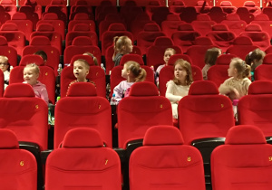 Dzieci siedzą na fotelach w kinie