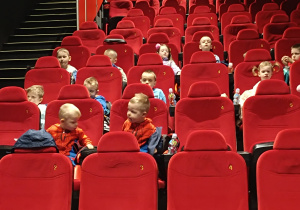 Dzieci siedzą na fotelach w kinie