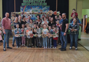 Dzieci z rodzicami z wykonaną ramką z kwiatami z materiałów recyklingowych