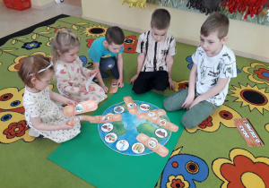 Dzieci podczas zabawy dydaktycznej na dywanie "Uleczymy Ziemię".