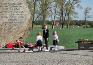 Dzieci składają kwiaty pod Obeliskiem.