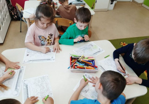 Dzieci siedzą przy stoliku i wykonują zadanie "Kubusiwego przyjaciela natury".