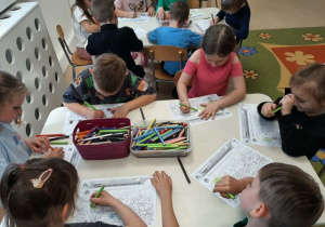 Dzieci siedzą przy stoliku i wykonują zadanie "Kubusiwego przyjaciela natury".