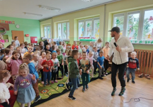 Przedszkolaki tańczą wraz z prowadzącym w rytm muzyki.