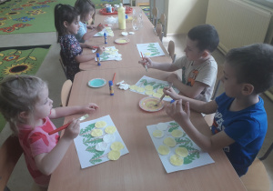 Dzieci podczas pracy plastycznej przy stolikach pt. "Mlecze"
