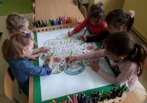 Dziewczynki kolorują ilustrację majowej łąki.