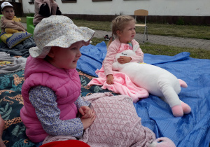 Dziewczynki w plenerowej strefie czytelniczej podczas akcji "Czytanie na polanie".