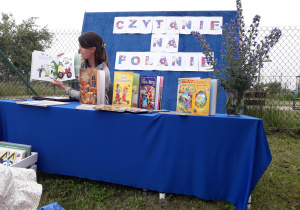 Pani Klaudia czyta dzieciom książkę podczas akcji "Czytanie na polanie".
