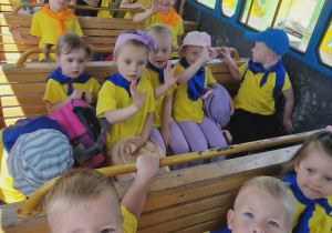 Dzieci siedzą w wagonie kolejki, która jedzie po terenie zoo