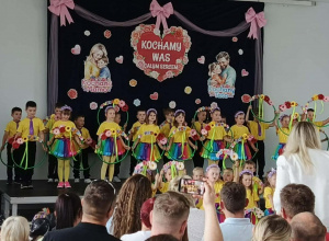Dzieci stoją na scenie z kolorowymi rekwizytami