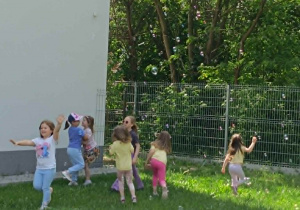 Dzieci na placu zabaw łapią bańki mydlane