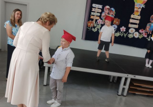 Pani dyrektor wręcza chłopcu dyplom ukończenia przedszkola.