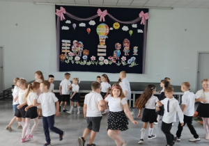 Przedszkolaki obracają się w parach podczas tańca.