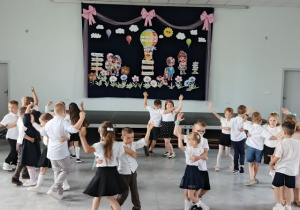 Przedszkolaki obracają się w parach podczas tańca.