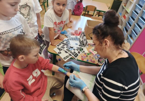 Pani robi chłopcu kolorowy tatuaż.
