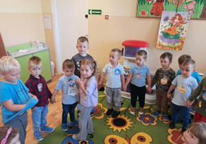 Dzieci stoją w kole, uczestniczą w zabawie muzycznej.