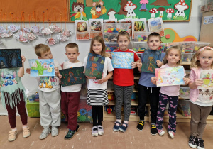 Dzieci stoją i trzymają swoje prace plastyczne