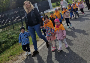 Dzieci z opiekunami na spacerze idą poboczem