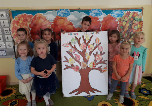 Grupa przedszkolaków prezentuje pracę plastyczną: "Drzewo życzliwości".