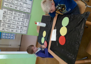 Dzieci naklejają kolorowe kółka na sygnalizator.