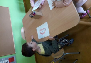 Chłopiec koloruje ilustrację uśmiechniętych ust.