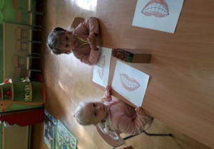 Dziewczynki kolorują ilustrację uśmiechniętych ust.